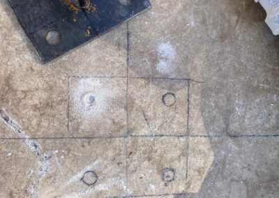 Drill plate on ground with pencil marks indicating where to drill holes