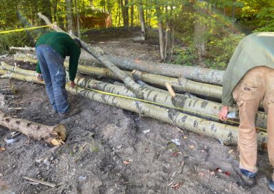 two people measuring logs with a measuring tape