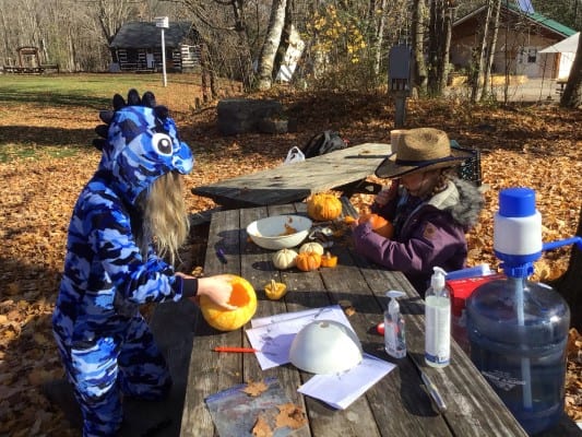 Campers carving pumpkins at a bench