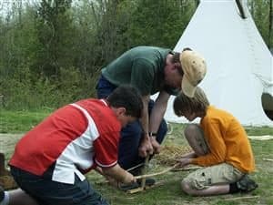 three people cutting branches