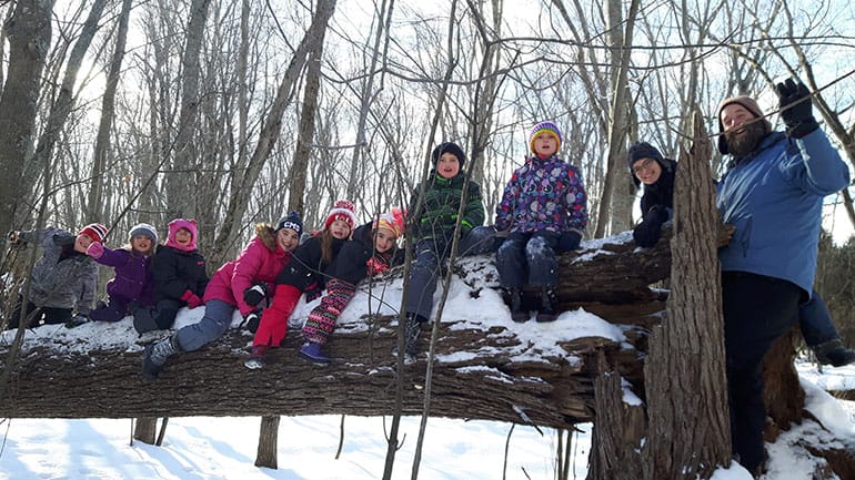 Campers posing on a log in winter